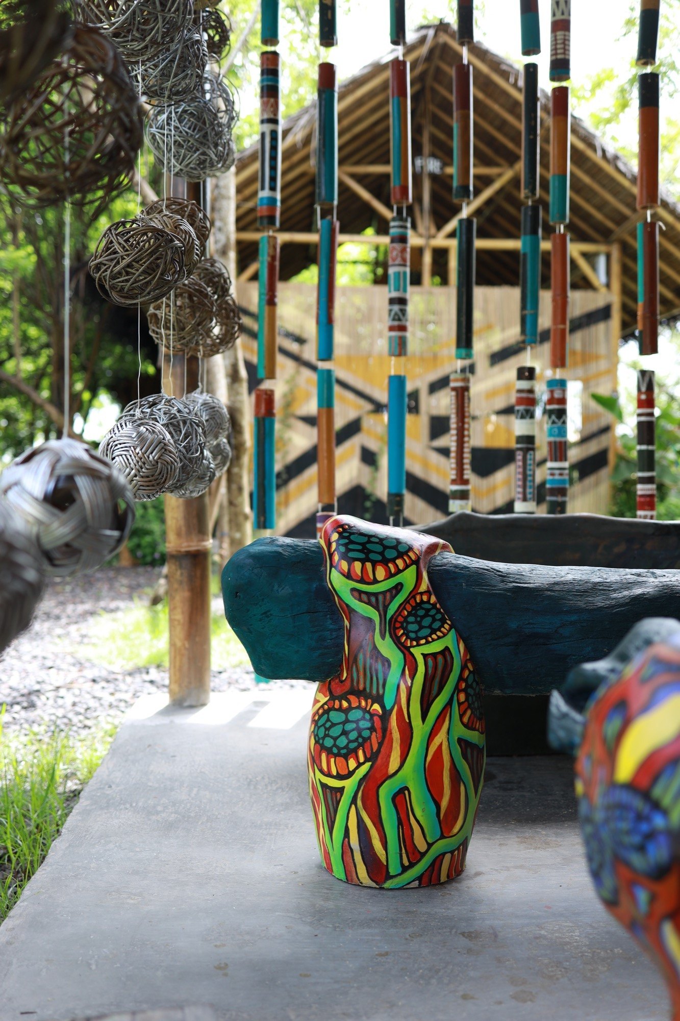 Vivid hand-painted totem and woven spheres against a patterned wall