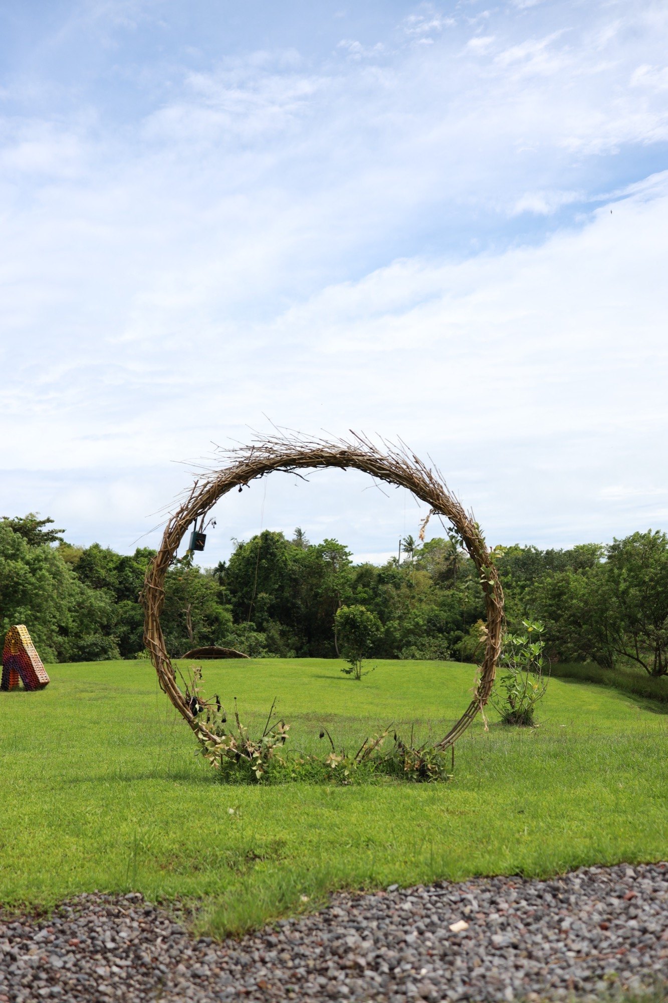 A large circular willow arch sculpture in a green field