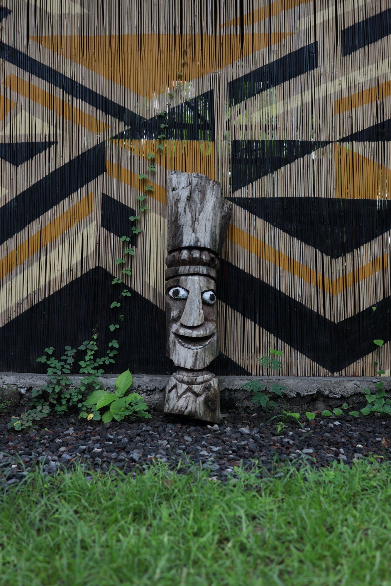 A carved wooden tiki totem on a patterned bamboo deck