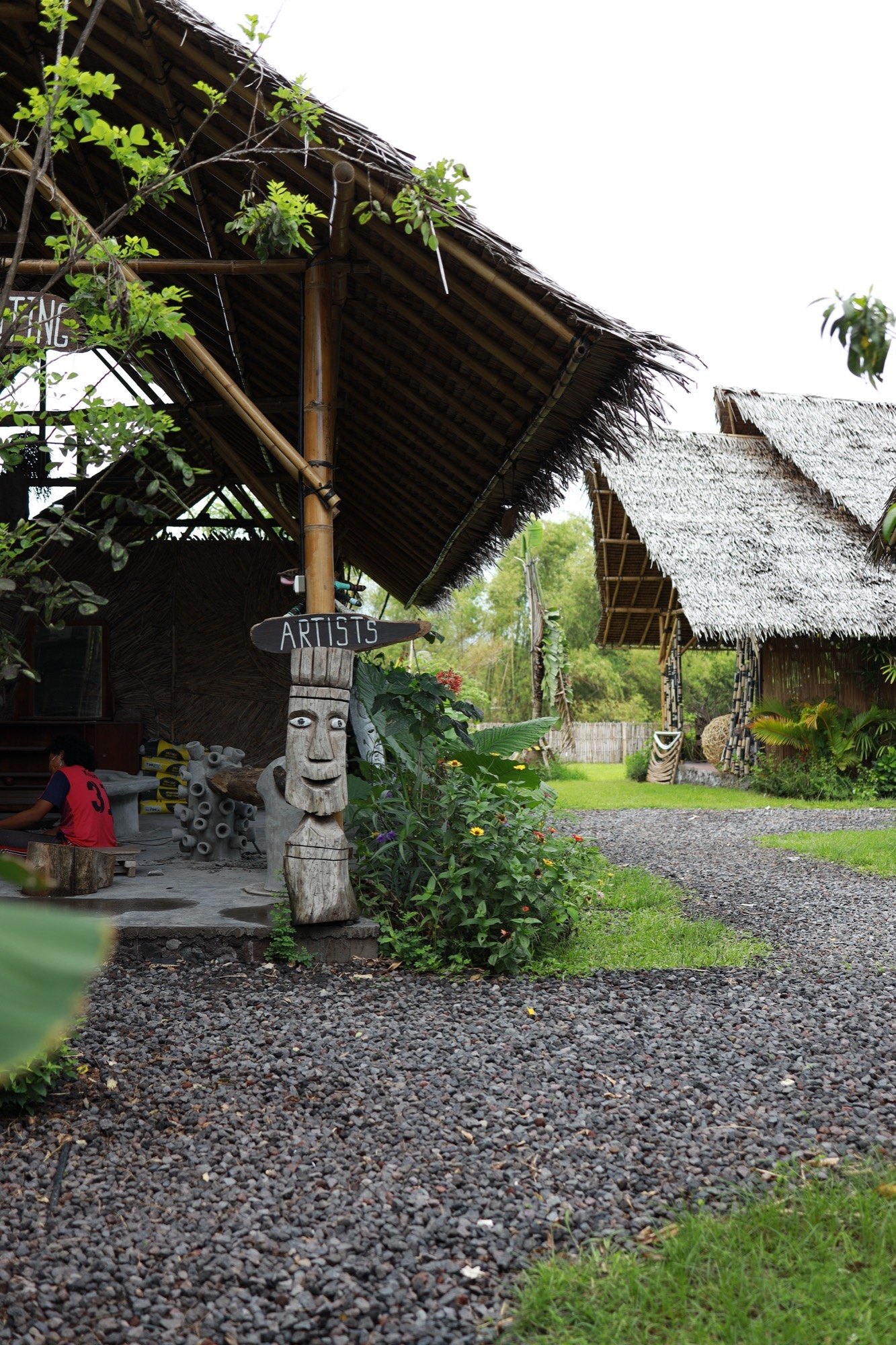 An ARTISTS signpost among thatched huts at Art Village