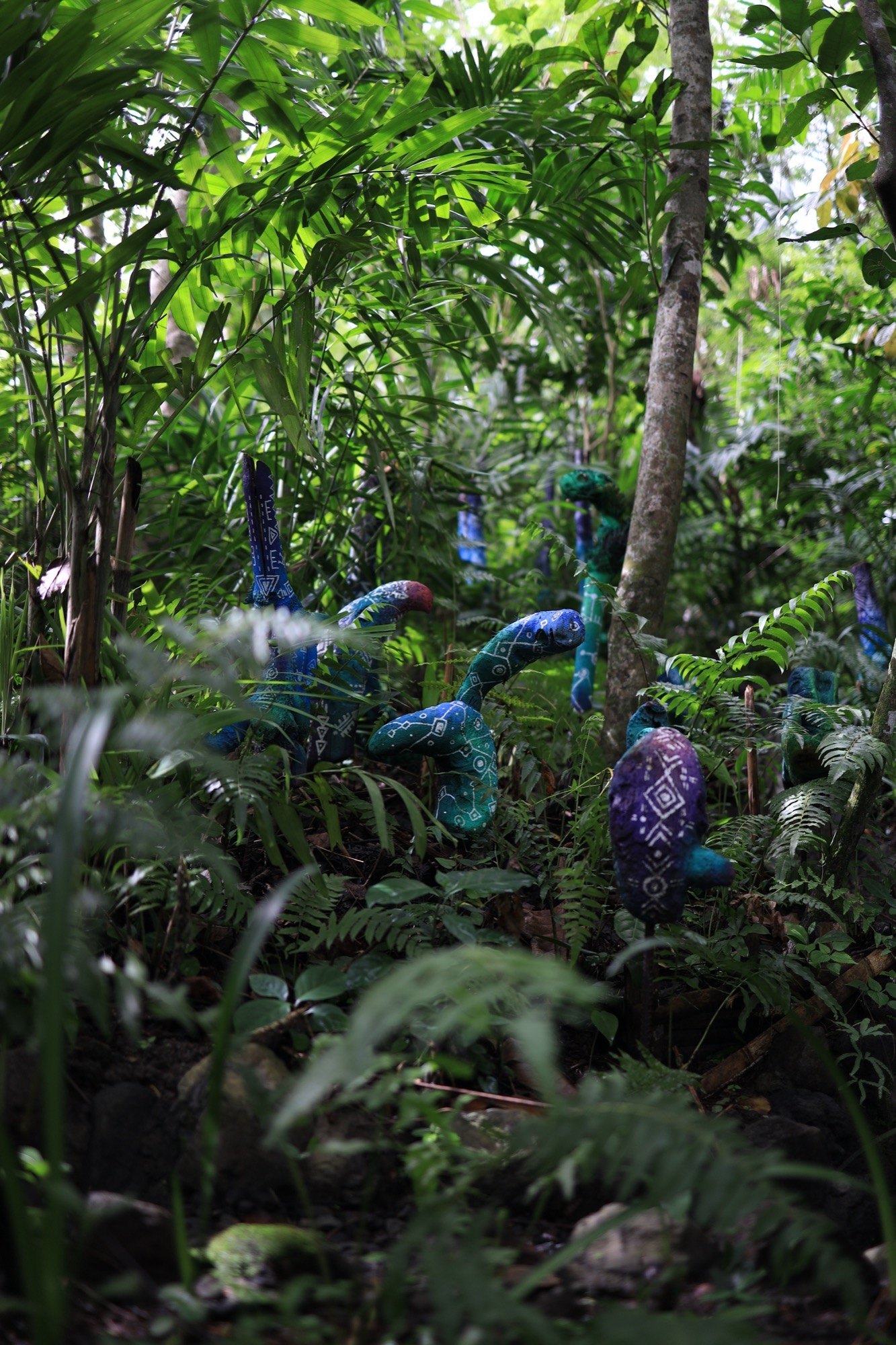Blue and purple painted creature sculptures nestled in the jungle